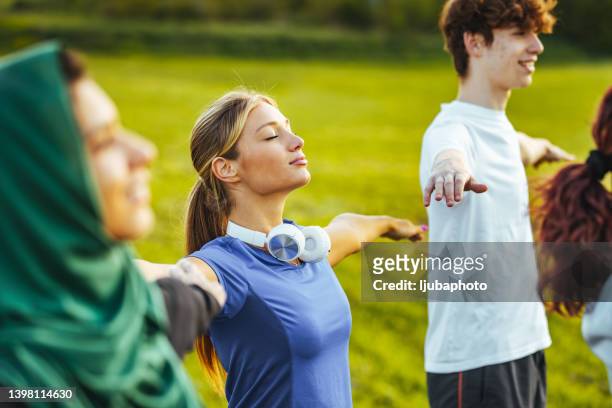 yoga class with woman and men doing breath exercising with stretched arms. - teenager yoga stock pictures, royalty-free photos & images