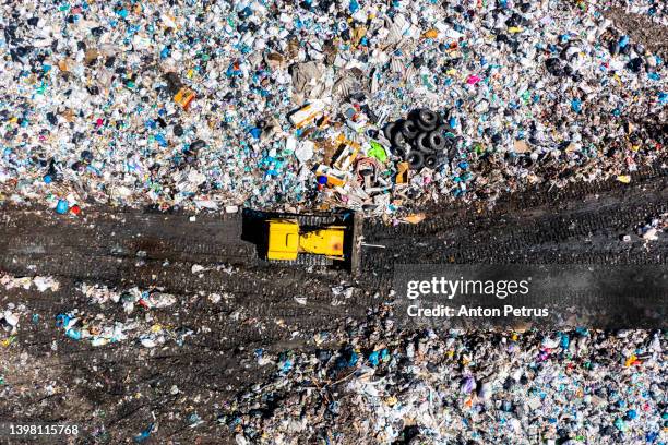 aerial view of bulldozer at city dump. the concept of pollution and excessive consumption - crash site stock pictures, royalty-free photos & images