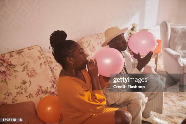 portrait of man and woman blowing up balloons. - blowing up balloon stock pictures, royalty-free photos & images