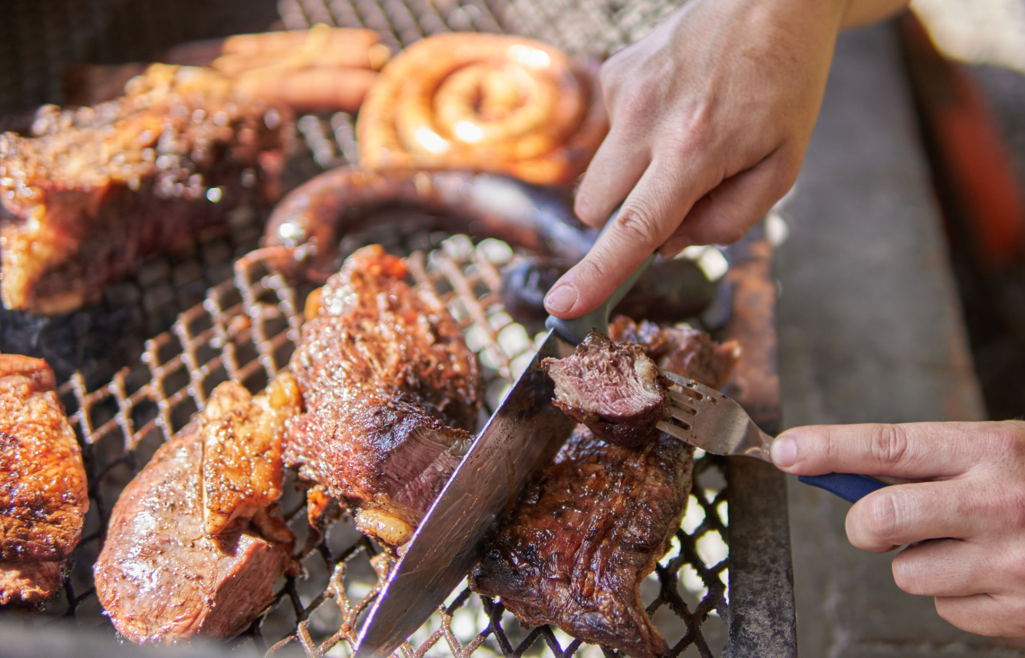 Mains d’homme faisant un barbecue pour le déjeuner. Des coupes de viande, des bobines de saucisse grillée et un boudin, du bœuf sur un gril en fer. Barbecue argentin traditionnel. Asado argentino Mains d’homme faisant un barbecue pour le déjeuner. Des coupes de viande, des bobines de saucisse grillée et un boudin, du bœuf sur un gril en fer. Barbecue argentin traditionnel. Asado argentino