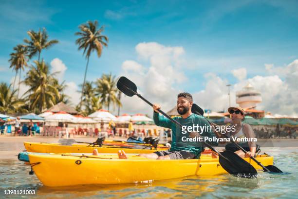 couple paddling kayak on the beach - sea kayaking imagens e fotografias de stock