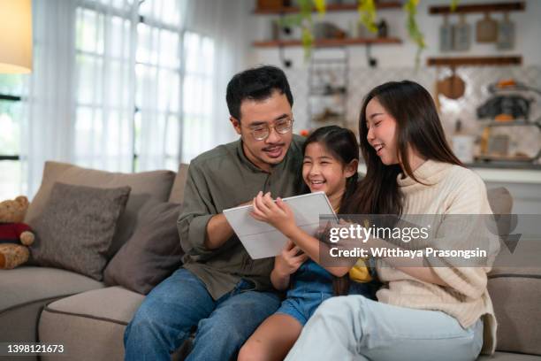 happy asian family using tablet, laptop for playing game watching movies, relaxing at home for lifestyle concept - couple school stockfoto's en -beelden