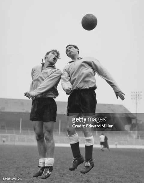 Duncan Edwards , Left Half for Manchester United jumps to head the football challenged by Bobby Robson , Inside Forward for West Bromwich Albion...