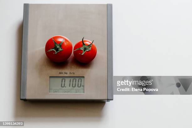 two red fresh tomatoes at the kitchen scale - kitchen scale stock pictures, royalty-free photos & images