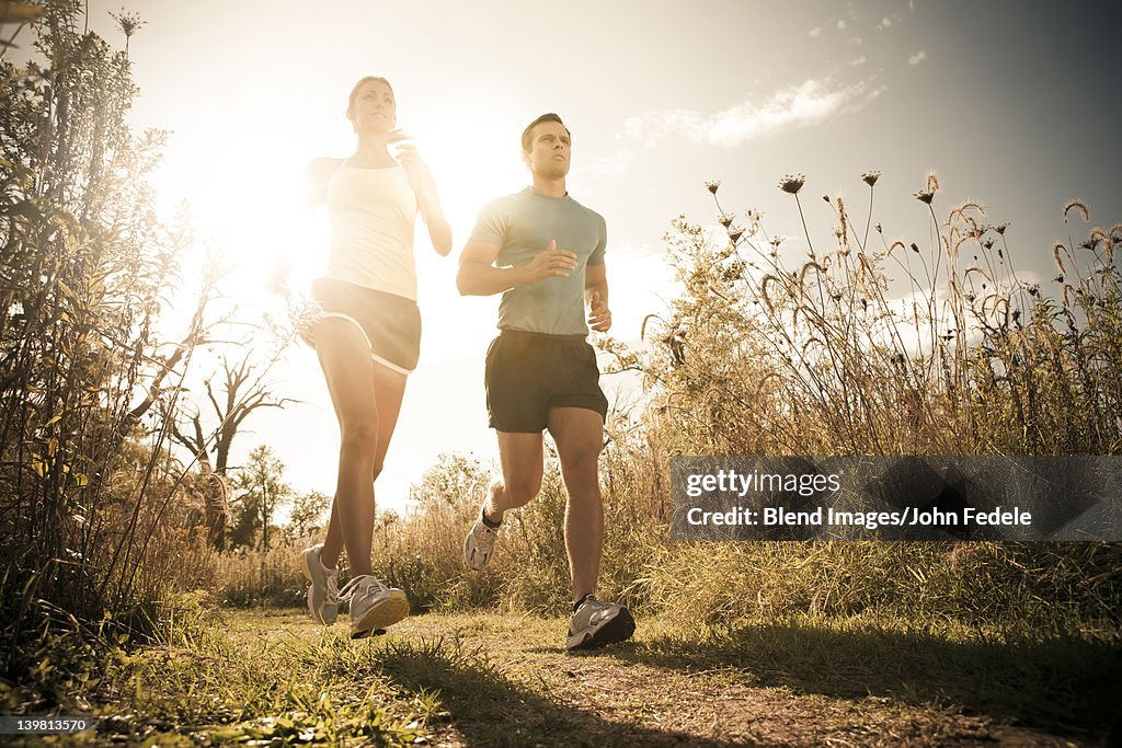 Caucasian couple running together on path