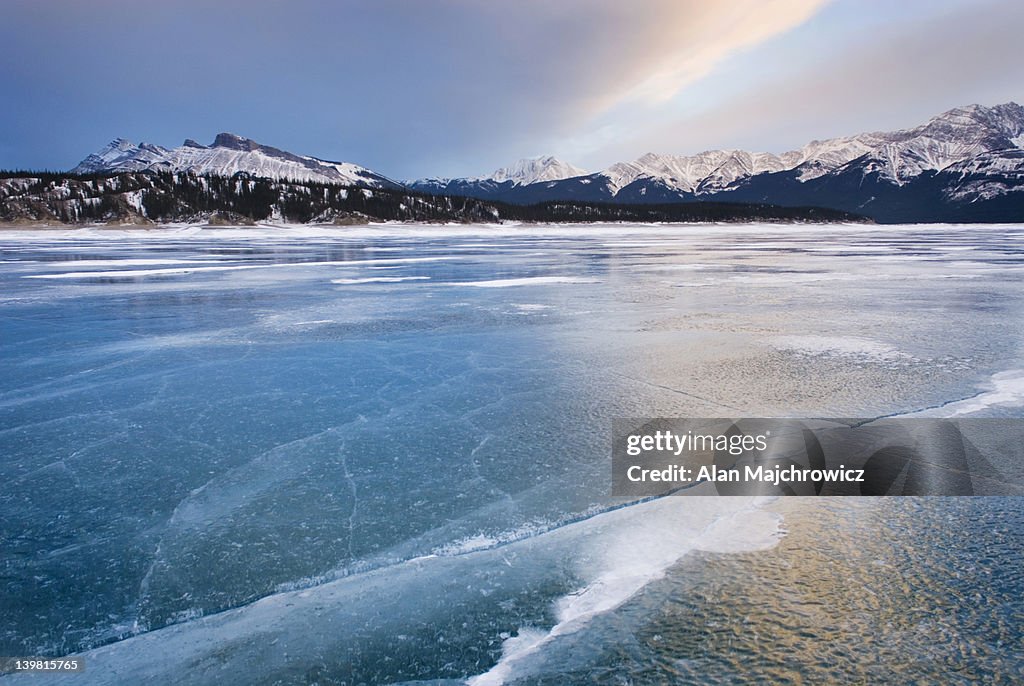 Clouds glowing in a winter sunset over the wind polished ice of Abraham Lake, Alberta, Canada