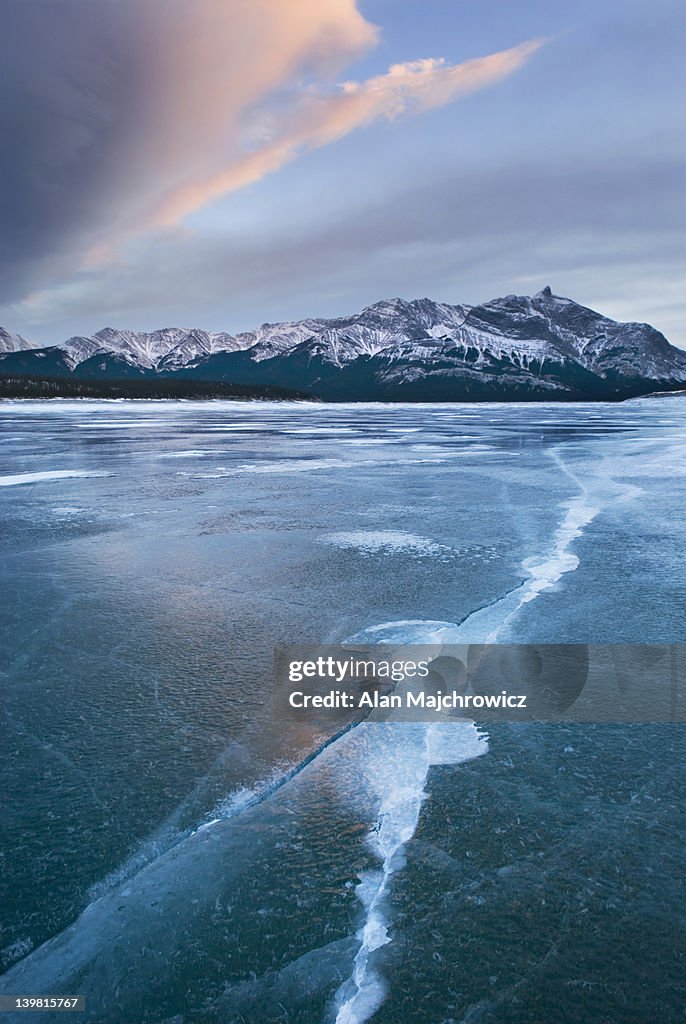Clouds glowing in a winter sunset over the wind polished ice of Abraham Lake, Alberta, Canada