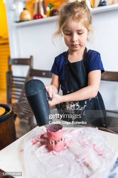 little blond girl blowing dry her pink clay craft pot with dryer. art and craft studio class. close up - atelier enfant photos et images de collection