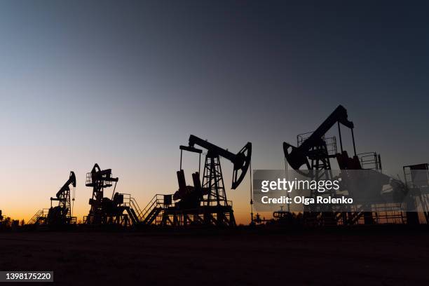the silhouette of oil pumps on a sunset sky with sun setting. environmental issue, pollution and damage, ecological risks. siberia. - fraccen stockfoto's en -beelden