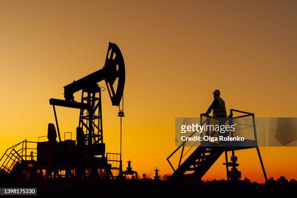 the silhouette oil pumps or nodding donkeys against dusk sky. oil and gas production, copy space - oil and gas industry stock pictures, royalty-free photos & images