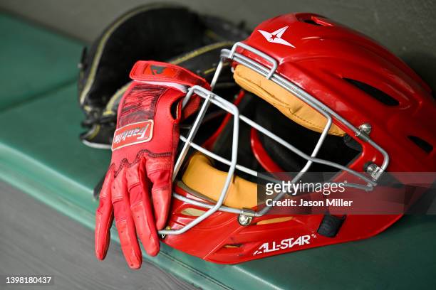 Franklin batting glove sits in the dugout with a catcher's glove and helmet prior to the game between the Cleveland Guardians and the Cincinnati Reds...