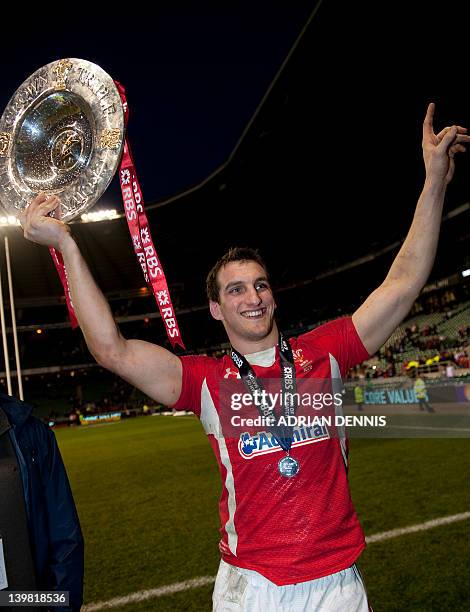 Wales' captain Sam Warburton holds the Triple Crown trophy as he walks off the field after beating England during the 6 Nations International rugby...