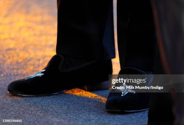 Prince William, Duke of Cambridge, wearing a pair of velvet evening slippers embroidered with a fighter plane design, attends the UK premiere and...