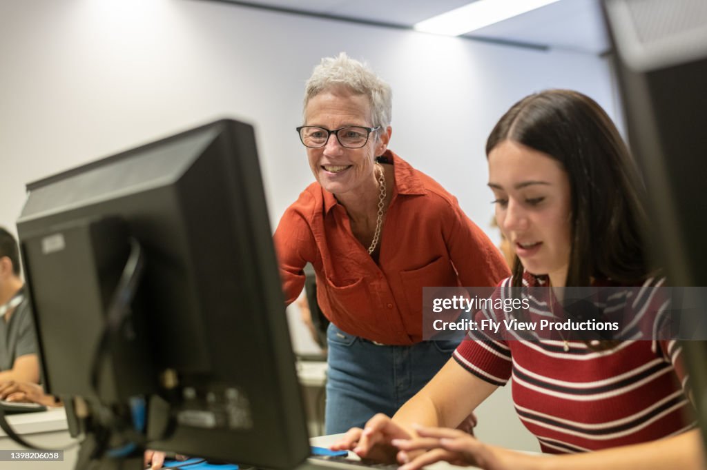 Teacher Helping High School Student With Computer Assignment High-Res ...
