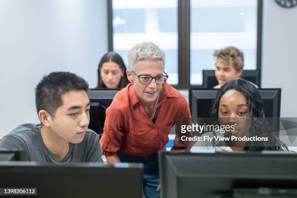 high school professor helping students with assignment in computer lab - computer equipment stock pictures, royalty-free photos & images