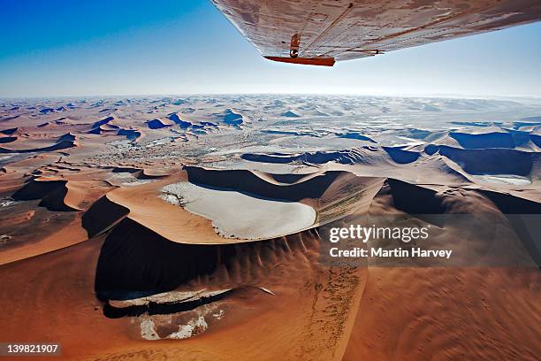 aerial view of sand dunes at sossusvlei in namib desert. wing tip visible of airplane. namib naukluft national park, namibia. - namibia airplane stock pictures, royalty-free photos & images