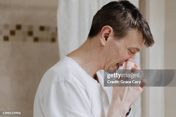 man blows his nose with facial tissue - snuit stockfoto's en -beelden