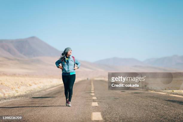 woman walking on an empty road - chile desert stock pictures, royalty-free photos & images