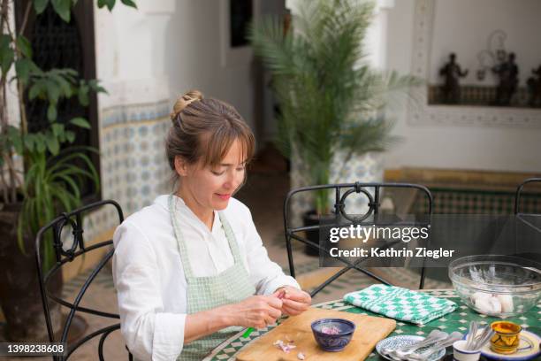 woman sitting at the table, peeling garlic - éplucher photos et images de collection