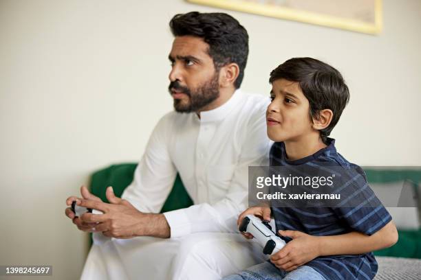 saudi father and son competing during video game - arabische muster stockfoto's en -beelden