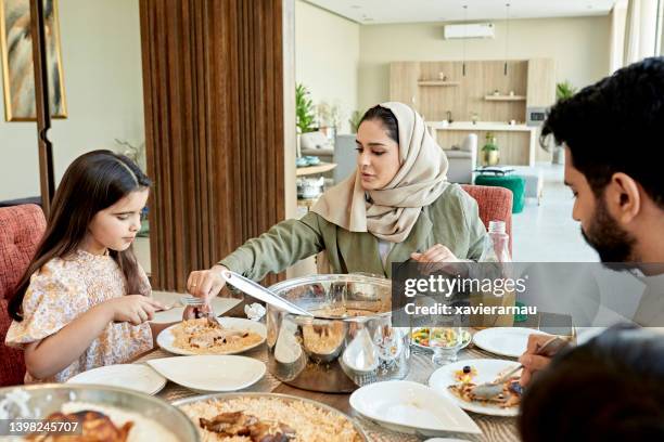 young saudi mother serving her daughter at dining table - mat från mellanöstern bildbanksfoton och bilder