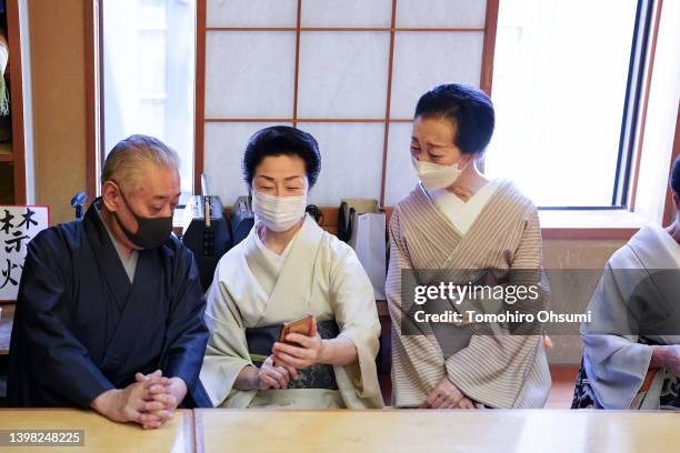 Performing artists and entertainers trained in traditional styles called "geisha" look at a smartphone during a training session on May 18, 2022 in...