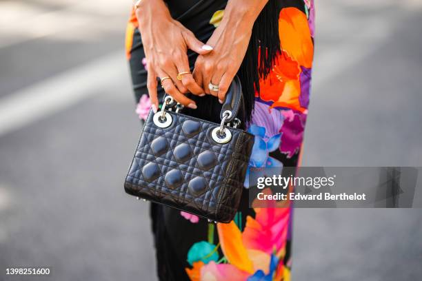 Hannah Romao wears a black with neon orange / purple / blue / green flower print pattern shoulder-off / asymmetric fringed long dress, a black shiny...