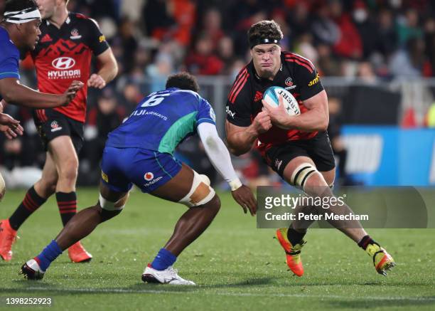 Scott Barrett of the Crusaders runs with the ball against Joseva Tamani of the Fijian Drua during the round 14 Super Rugby Pacific match between the...