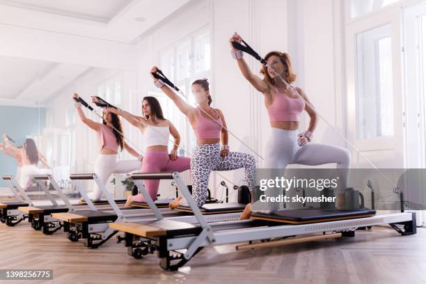 gruppe von frauen, die auf pilates-geräten trainieren. - reformer stock-fotos und bilder