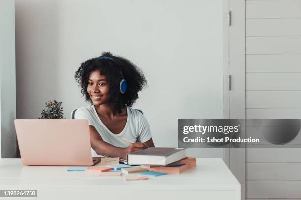 young woman working on laptop with headphone at home in living room. - vpn stock pictures, royalty-free photos & images