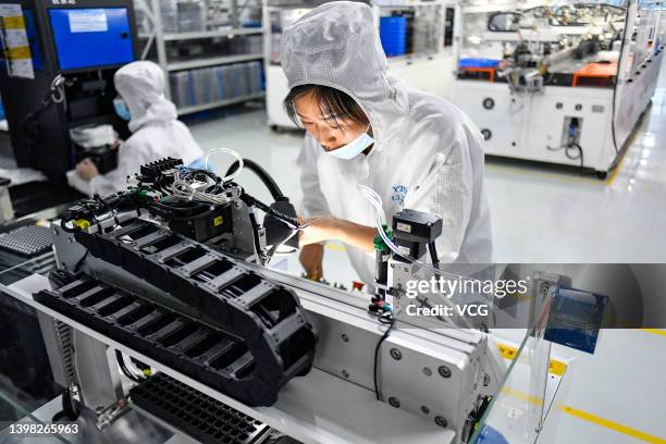 Employees work on the production line of optical lens for CCTV cameras at a factory of Dongguan Yutong Optical Technology Co., Ltd on May 17, 2022 in...