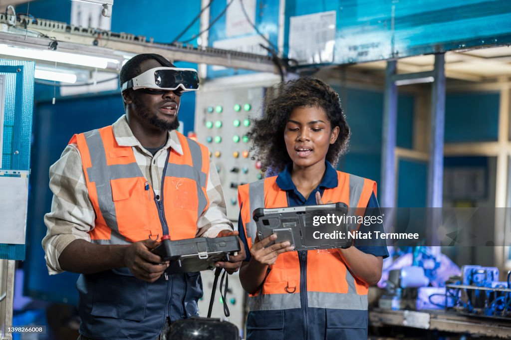 AI and Machine Learning Can Be Improve Productivity in Manufacturing Industry. Female Mechanical Engineer and Robotic welding operator. They are using VR glasses to simulation assembly welding before starting the actual production process.