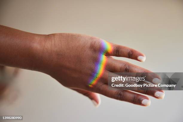 regenbogenfarbenes licht, das auf die hand einer frau bricht - lichtbrechung stock-fotos und bilder