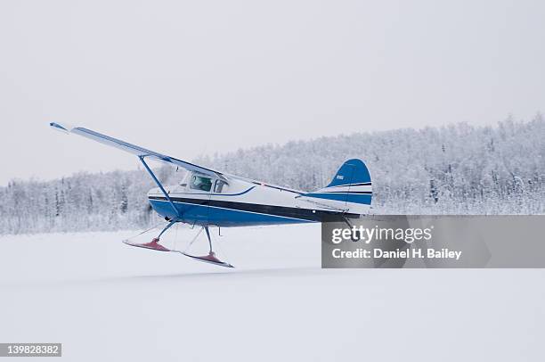 alaska bush pilot flying a cessna 170 airplane with skis, winter, taking off from a frozen lake, alaska - jet ski stock-fotos und bilder