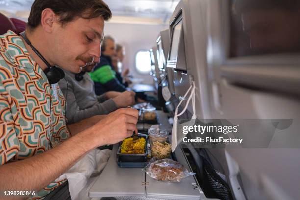 caucasian male tourist having a meal at the airplane while traveling - plane food stock pictures, royalty-free photos & images