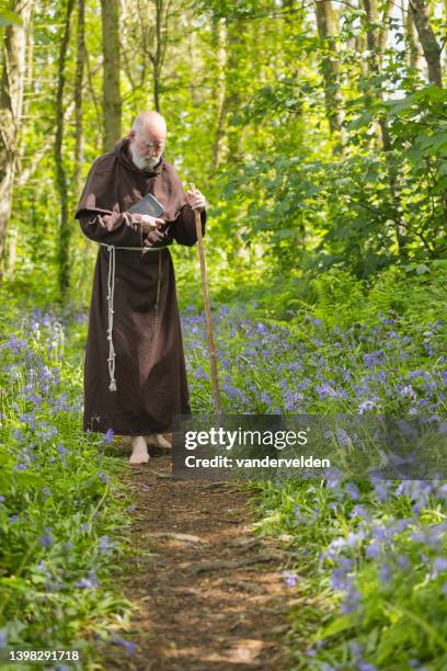 älterer mönch, der im wald spazieren geht - monk stock-fotos und bilder