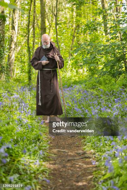 monje anciano caminando por el bosque - blue flower fotografías e imágenes de stock