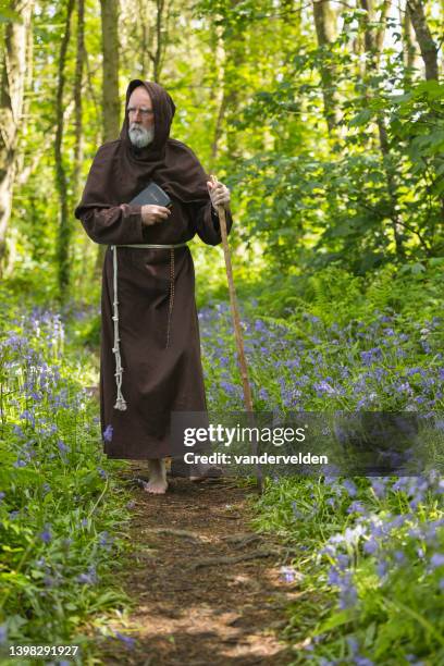 monje anciano caminando por el bosque - blue flower fotografías e imágenes de stock