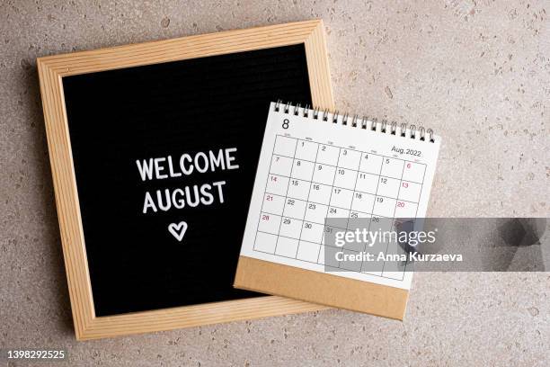 close-up of letter board with text “welcome august” and august 2022 desk calendar, top view. hello summer concept. - august stock pictures, royalty-free photos & images