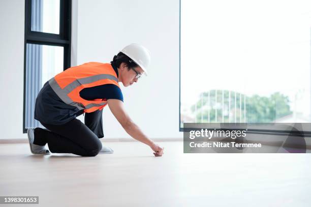 hardwood floor checklist and diagnostics in real estate industry. male japanese construction engineer examining excessive gaps of parquet hardwood floor before giving the house to the customer. - permanence stock pictures, royalty-free photos & images