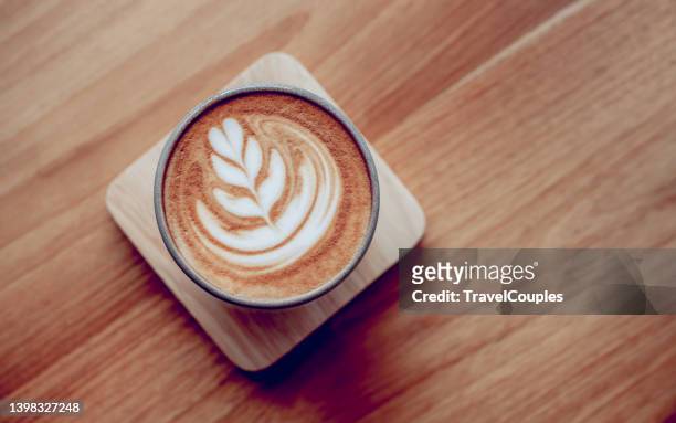 coffee latte art in cafe at morning time. latte art coffee on wooden table in coffee shop. cups of cappuccino on wooden background - coffee heart fotografías e imágenes de stock
