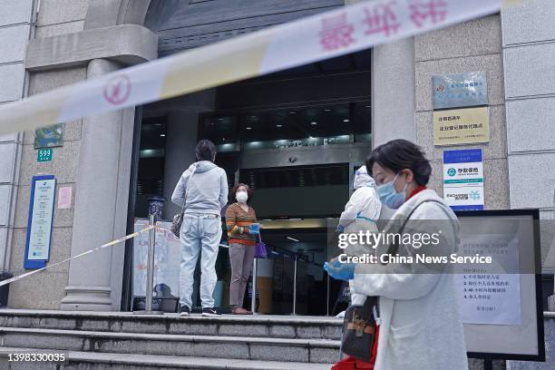 Customers wearing face masks line up to enter a branch of Shanghai Rural Commercial Bank on the reopening day on May 20, 2022 in Shanghai, China....