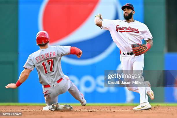 Shortstop Amed Rosario of the Cleveland Guardians throws out TJ Friedl at first as Kyle Farmer of the Cincinnati Reds is out at second for a double...