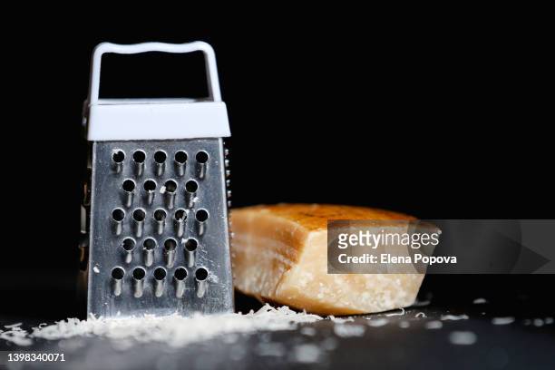 piece of parmesan and cheese grater against black background - grater stock pictures, royalty-free photos & images