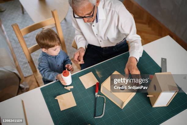 high angle view of grandpa and grandson making a birdhouse - glue stock pictures, royalty-free photos & images