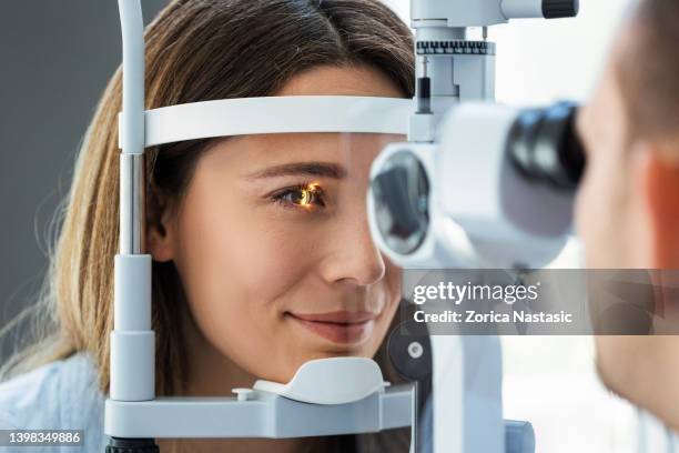 beautiful young girl checking the eye vision in ophthalmology clinic - 20th anniversary screening of wag the dog stockfoto's en -beelden