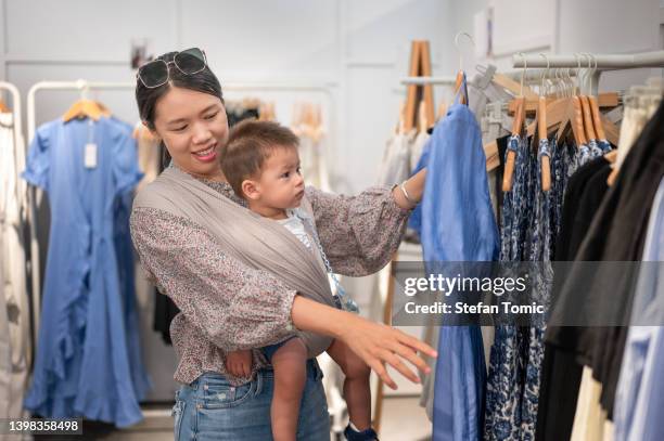 woman doing shopping with her baby boy in the stroller - baby boutique stock pictures, royalty-free photos & images