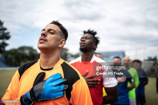 fußballspieler hören hymne auf dem feld - nationalhymne stock-fotos und bilder