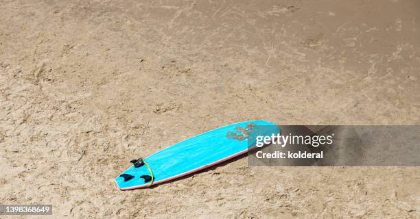 blue surfboard on sandy beach - planche de surf photos et images de collection