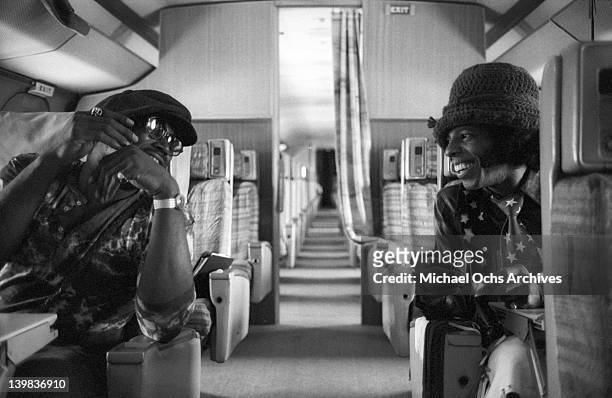 Sly Stone of the psychedelic soul group 'Sly and the Family Stone' talks with a man as they sit aboard a plane in San Diego to do a radio interview...